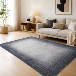 Tapis acoustique Pure Tone gris installé dans un salon lumineux, avec un centre gris clair en dégradé et une bordure anthracite plus soutenue, associé à un canapé beige et du mobilier en bois.
