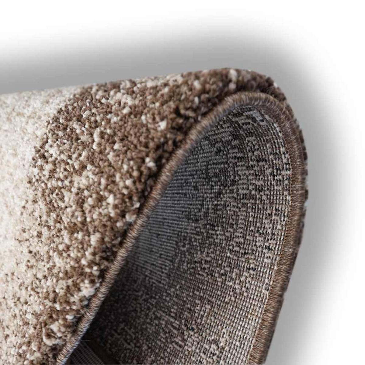 Détail du tapis acoustique Pure Tone beige replié, montrant l’épaisseur de la surface textile, la bordure cousue et la structure de son envers.
